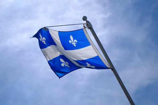 national Quebec flag in Canada fluttering in the wind on blue sky