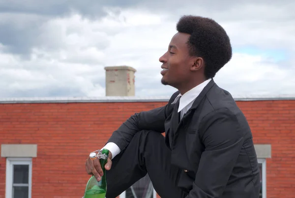 Ung affärsman dricka vin flaska sitter utomhus och leende — Stockfoto
