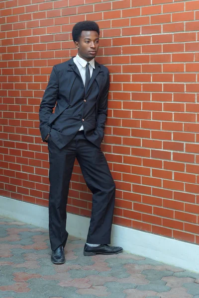 Joven hombre de negocios con traje y corbata de longitud completa pared de ladrillo —  Fotos de Stock