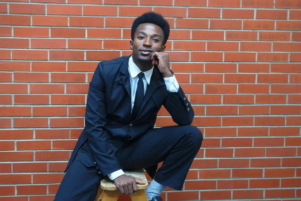 Jovem empresário sentado terno e gravata tijolo parede negócio sorrindo retrato — Fotografia de Stock