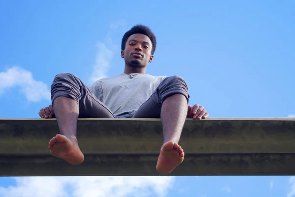 Ung man sitter barfota låg vinkel se blå himmel — Stockfoto