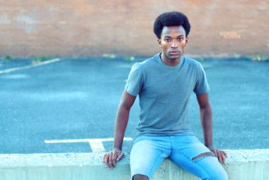 Kentsel şehir Park içinde beton duvara oturan yakışıklı genç adam 