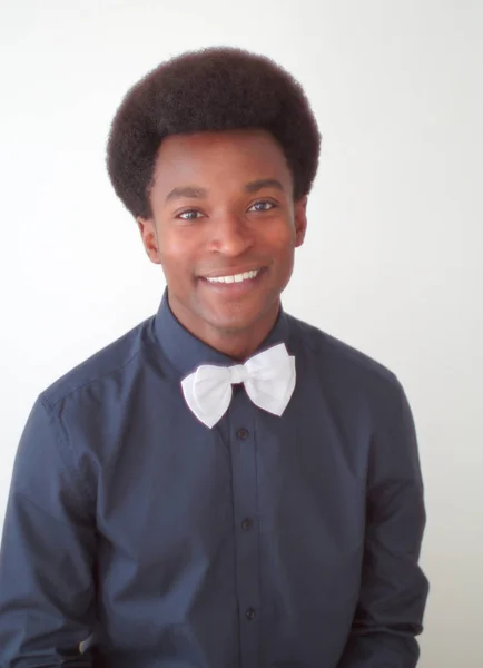 Fiatal férfi fekete póló csokornyakkendő stúdió portré mosolyogva — Stock Fotó
