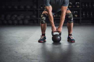 Adam bir su ısıtıcısı çan çapraz bir uygun spor salonunda kapma tutuyor