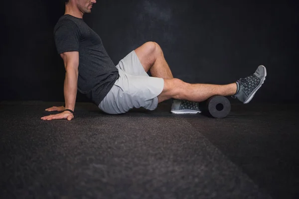 Spor salonunda yerde bir köpük rulo kullanan adam