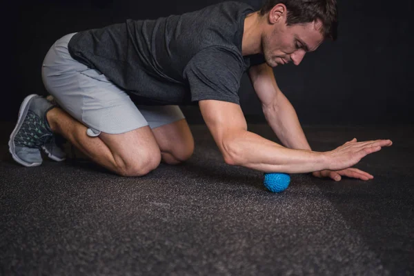Spor salonunda yerde bir köpük rulo kullanan adam
