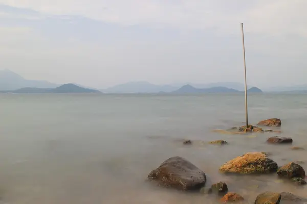 Felsbrocken ragen aus glatter, welliger See — Stockfoto