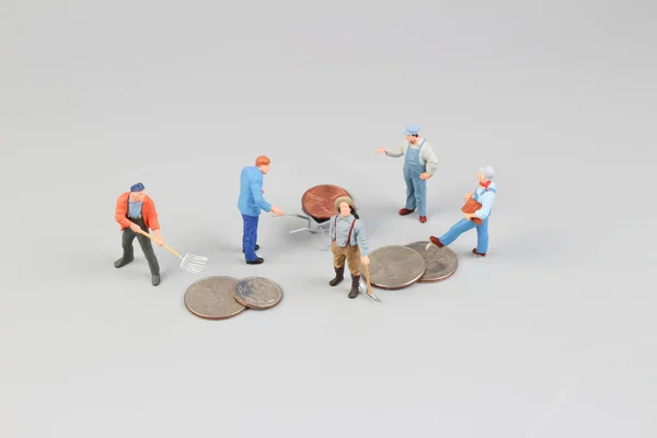 Работники Mini собирают монеты на месте — стоковое фото