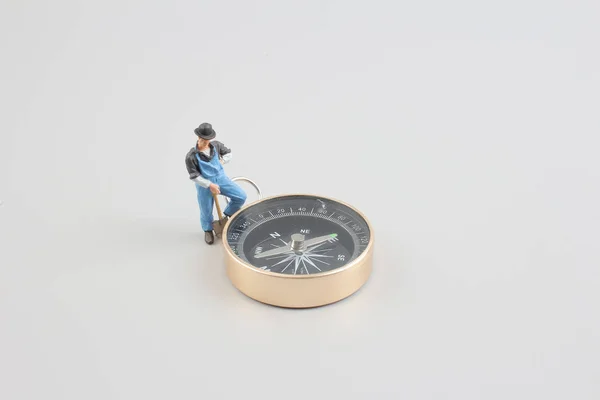Mini figure standing on a compass — Stock Photo, Image