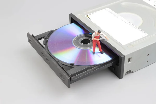 Миниатюрный инженер и рабочий, закрепленный на чистом CD ROM — стоковое фото