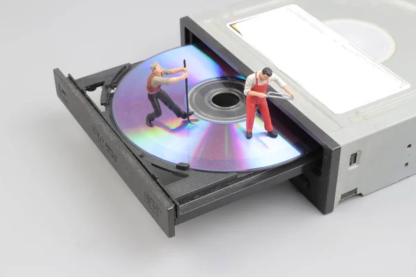 Miniature engineer and worker fixed to clean CD rom — Stock Photo, Image