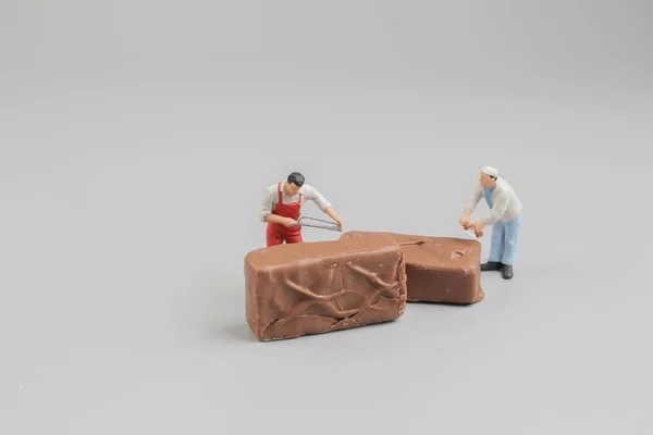 Miniarbeiter schneidet ein Stück Schokolade — Stockfoto