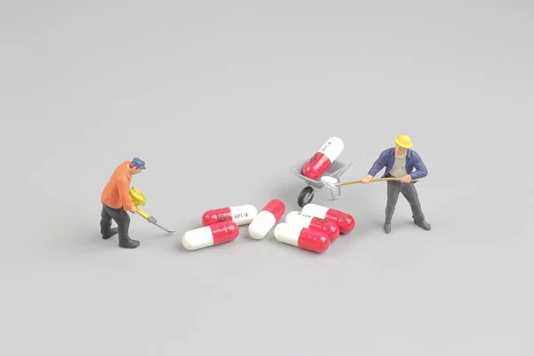 Arbetaren av siffran framför piller — Stockfoto