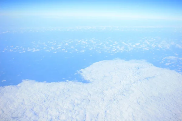 Blick aus dem Flugzeugfenster über die Wolken und den blauen Himmel — Stockfoto