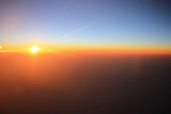 O pôr do sol acima das nuvens no avião — Fotografia de Stock