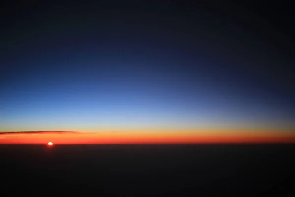 Le coucher du soleil au-dessus des nuages sur l'avion — Photo