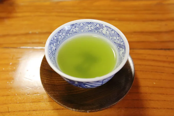 Ood arka plan üzerinde beyaz bir fincan yeşil çay — Stok fotoğraf