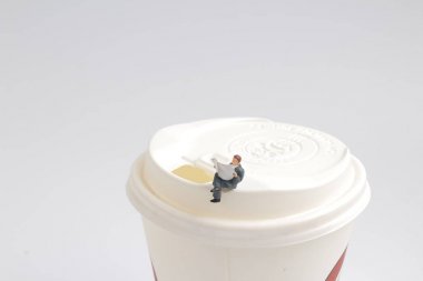 Mini figür oturmak ve kapak üzerinde gazete okumak