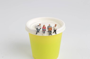  Mini figür oturma ve kağıt bardak üzerinde okuma 