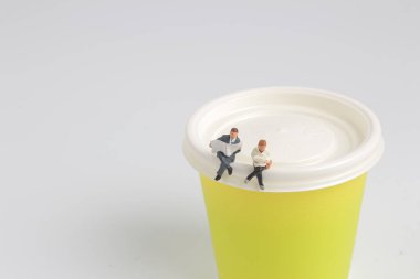  Mini figür oturma ve kağıt bardak üzerinde okuma 