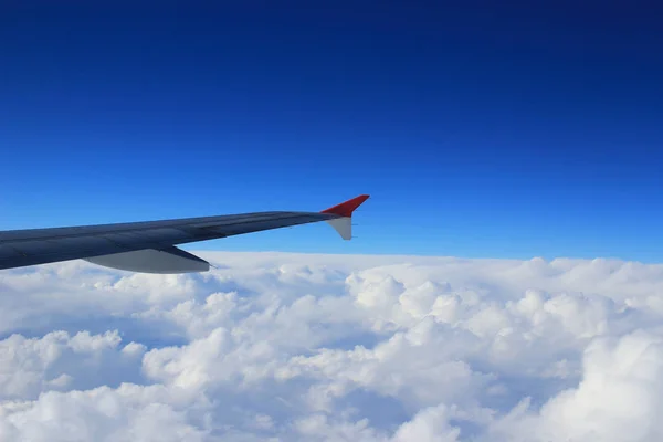 Vista del cielo nuboso desde la ventana del avión al lado de un ala — Foto de Stock