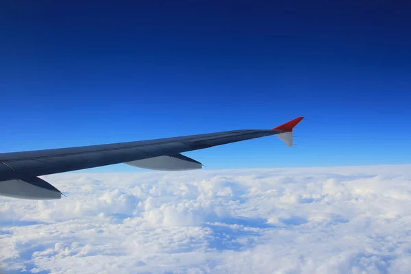 Vista del cielo nuboso desde la ventana del avión al lado de un ala — Foto de Stock