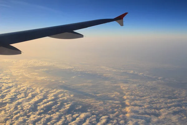 Φτερό ενός αεροπλάνου που πετούν πάνω από τα σύννεφα στο ηλιοβασίλεμα — Φωτογραφία Αρχείου