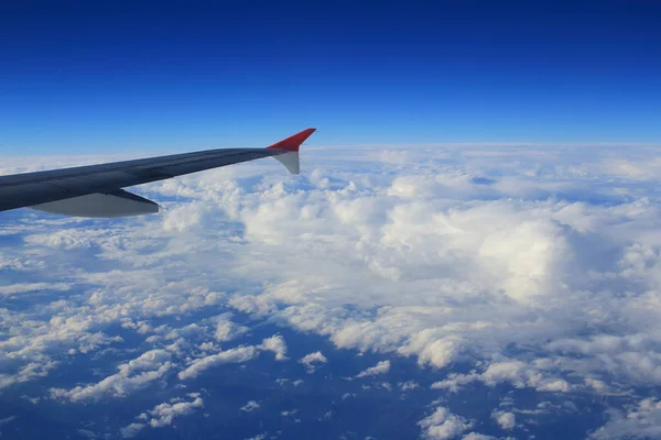 Vista del cielo nuboso desde la ventana del avión al lado de un ala — Foto de Stock