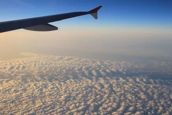 Ala de un avión volando sobre las nubes al atardecer —  Fotos de Stock