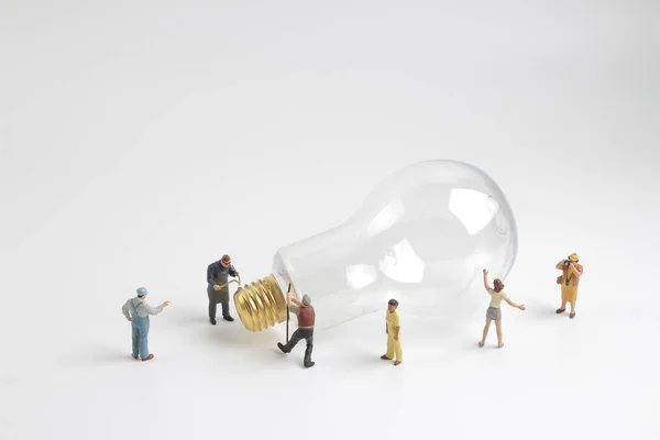 Figurengruppe arbeitet an einer Glühbirne — Stockfoto