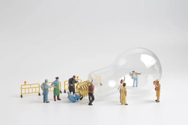 Группа фигур, работающих над лампочкой — стоковое фото