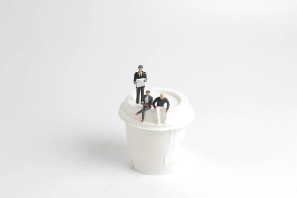 The Mini people reading and sitting on cup — стоковое фото