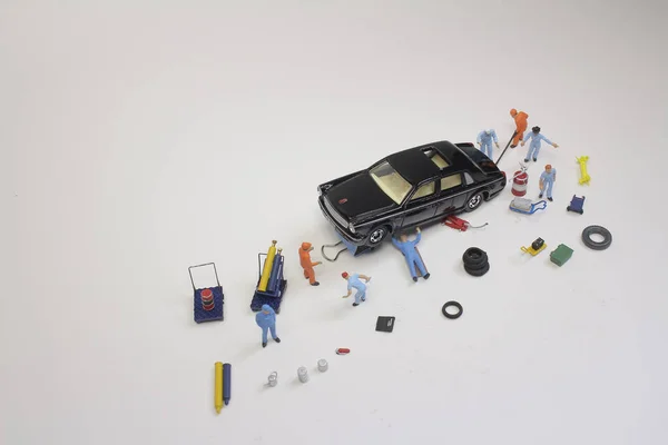 A mini mechanics replacing a punctured tyre of a car — Stock Photo, Image