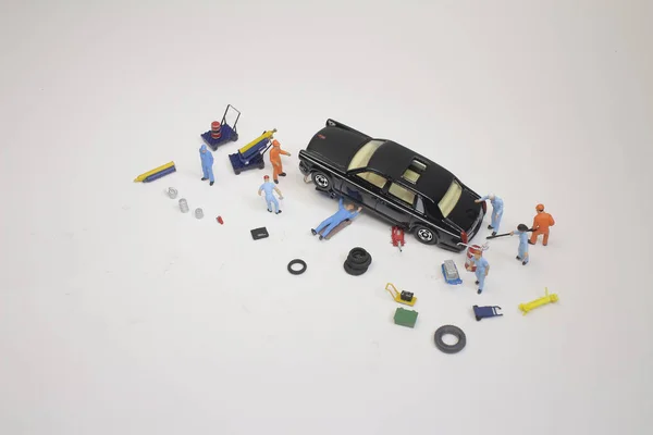 Un mini mecánico sustituyendo un neumático pinchado de un coche — Foto de Stock