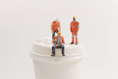 Kağıt bardakta oturan mini işçi figürleri.