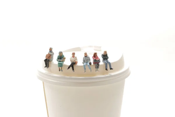 Мини-люди сидят на бумажной чашке, пьют кофе и ждут . — стоковое фото