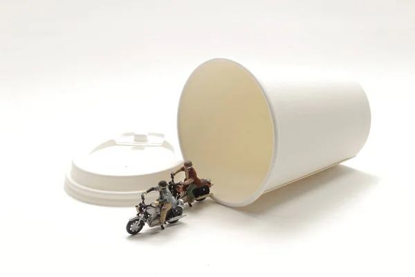 Una mini figura paseo motocicleta alrededor de la taza de papel — Foto de Stock