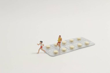 İlaç kullanan bir grup kadın ve erkek minyatür figür.