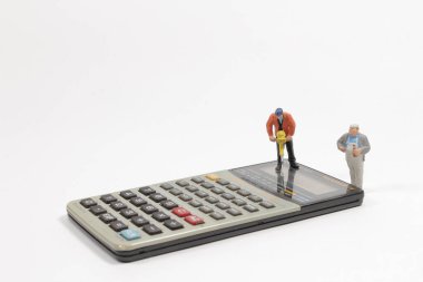 Hesap makinesindeki mini figürlü işçiler.