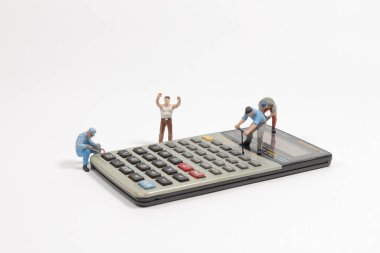 Hesap makinesindeki mini figürlü işçiler.
