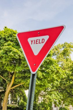 Red and white triangular sign letting motorists know they have to yield the right of way clipart