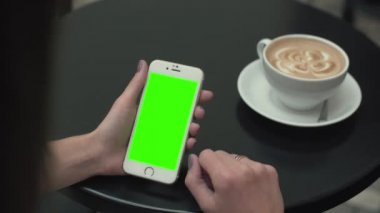 Bir cep telefonu ile yeşil ekran kullanan kadın