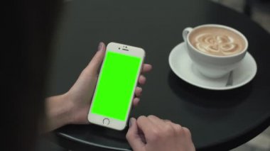 Bir cep telefonu ile yeşil ekran kullanan kadın