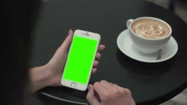 Bir cep telefonu ile yeşil ekran kullanan kadın