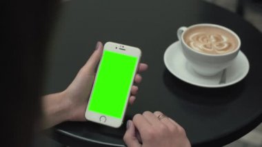 Bir cep telefonu ile yeşil ekran kullanan kadın