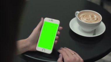 Bir cep telefonu ile yeşil ekran kullanan kadın