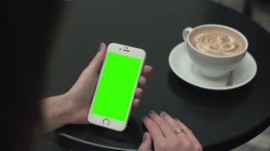 Bir cep telefonu ile yeşil ekran kullanan kadın