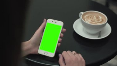 Bir cep telefonu ile yeşil ekran kullanan kadın