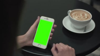 Bir cep telefonu ile yeşil ekran kullanan kadın