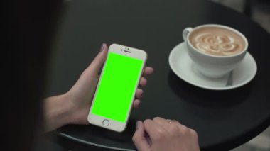 Bir cep telefonu ile yeşil ekran kullanan kadın